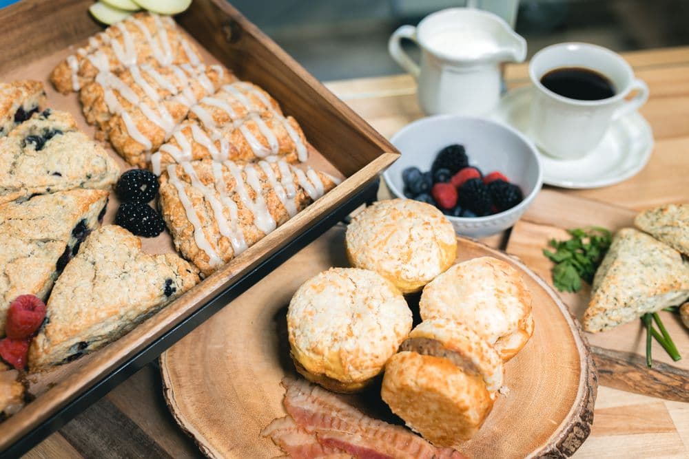 Assortment of Savannah Scone Company scones, biscuits, fresh berries, and coffee on a wooden table