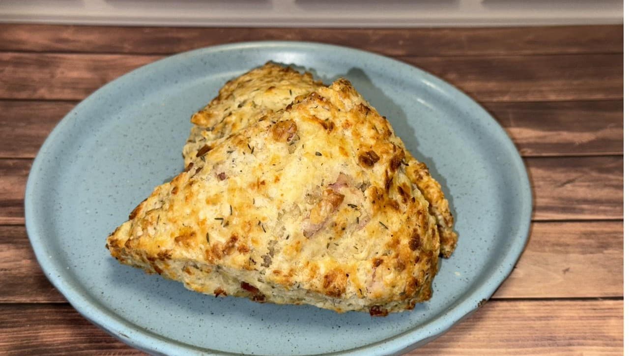 Two savory scones with cheese and herbs on a blue plate