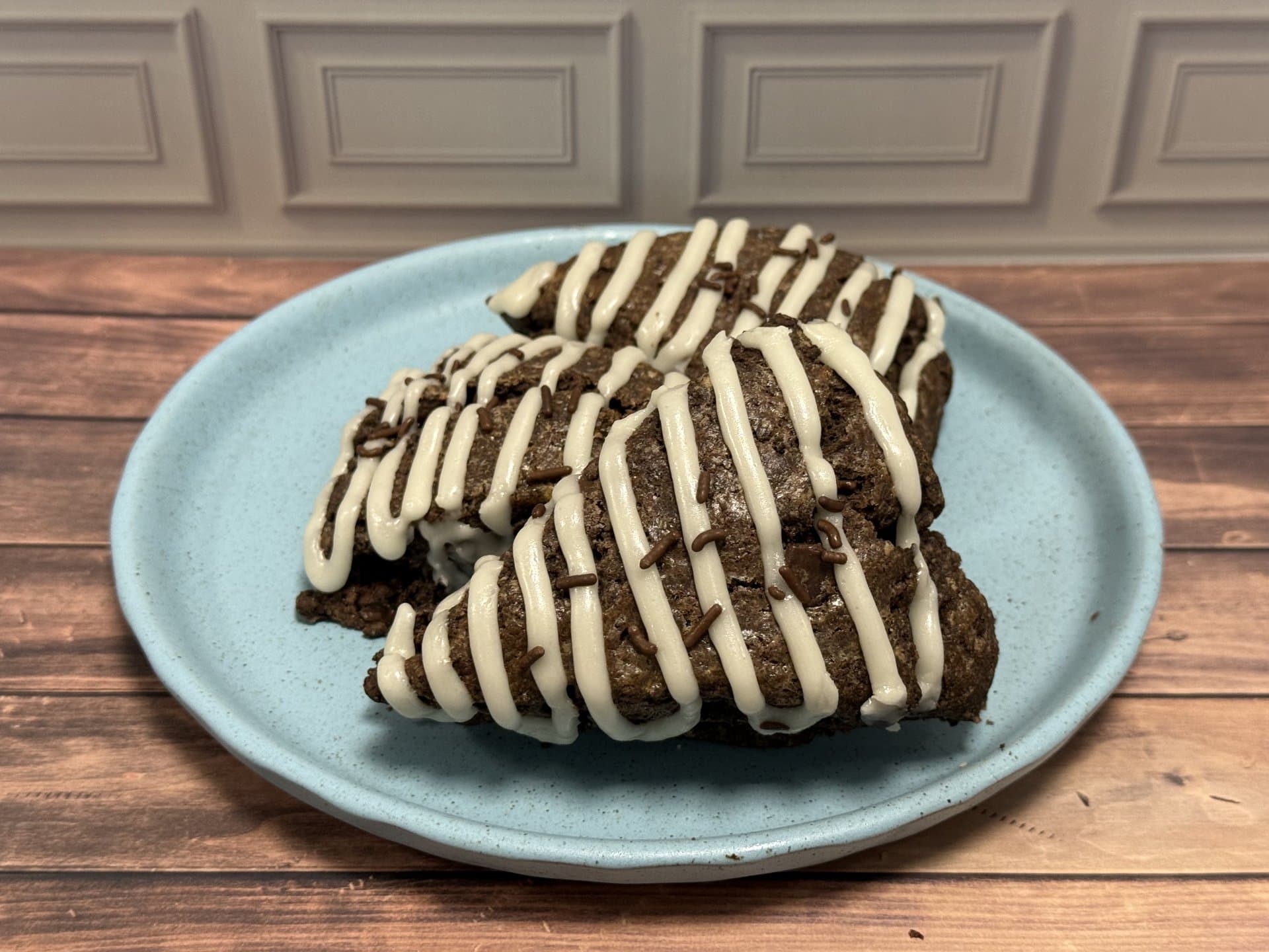 Chocolate scones with vanilla icing on a blue plate