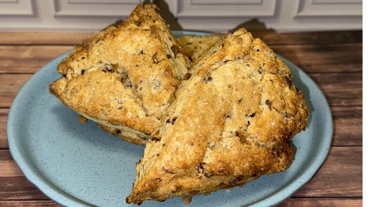 Two triangle scones with golden, sugar-topped crusts on a pale blue plate.